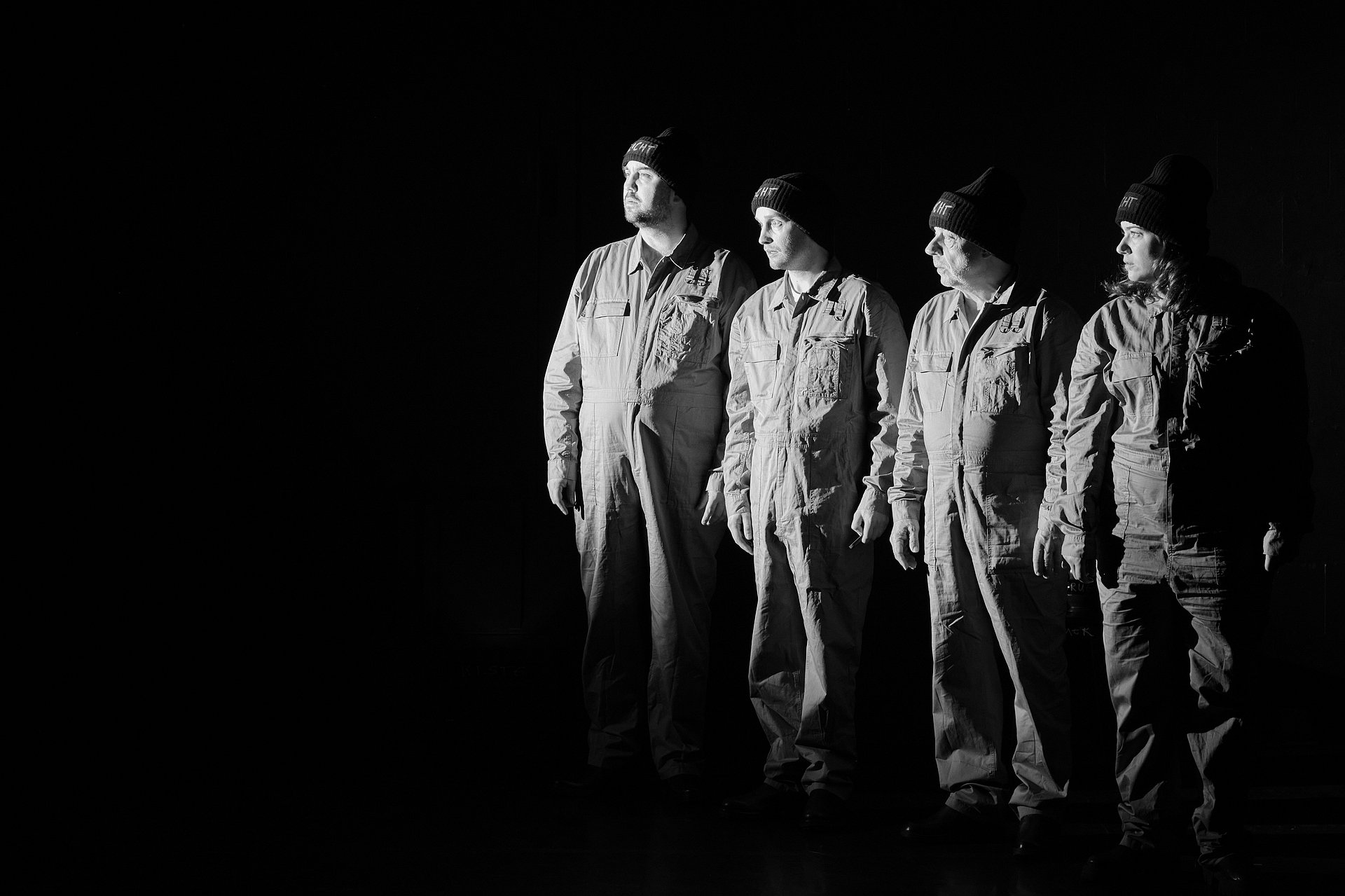 vier Schauspieler in militärischer Kleidung, schwarzweiß vor schwarzem Hintergrund