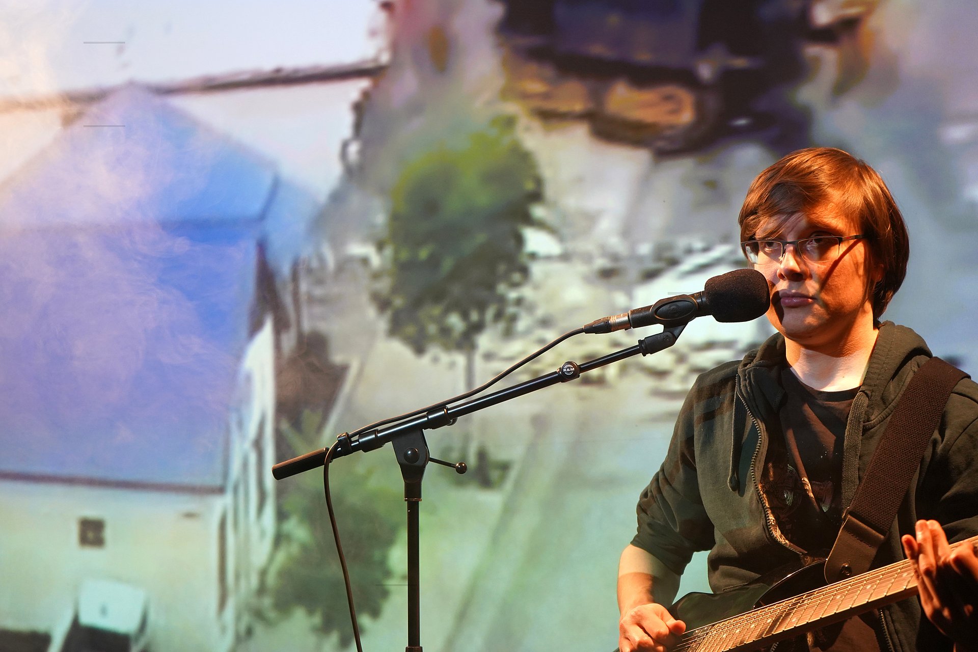 Schauspieler mit Gitarre am Mikrofon