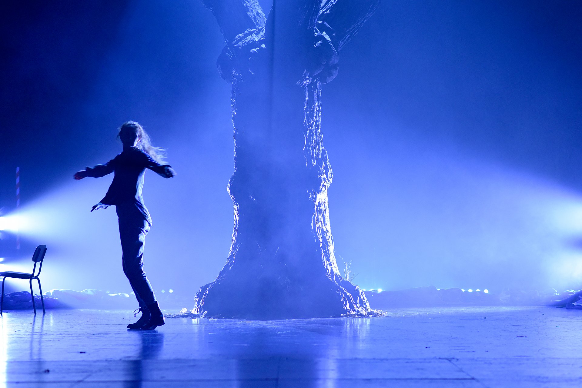 Schauspielerin vor Baum auf in blaues Licht getauchter Bühne