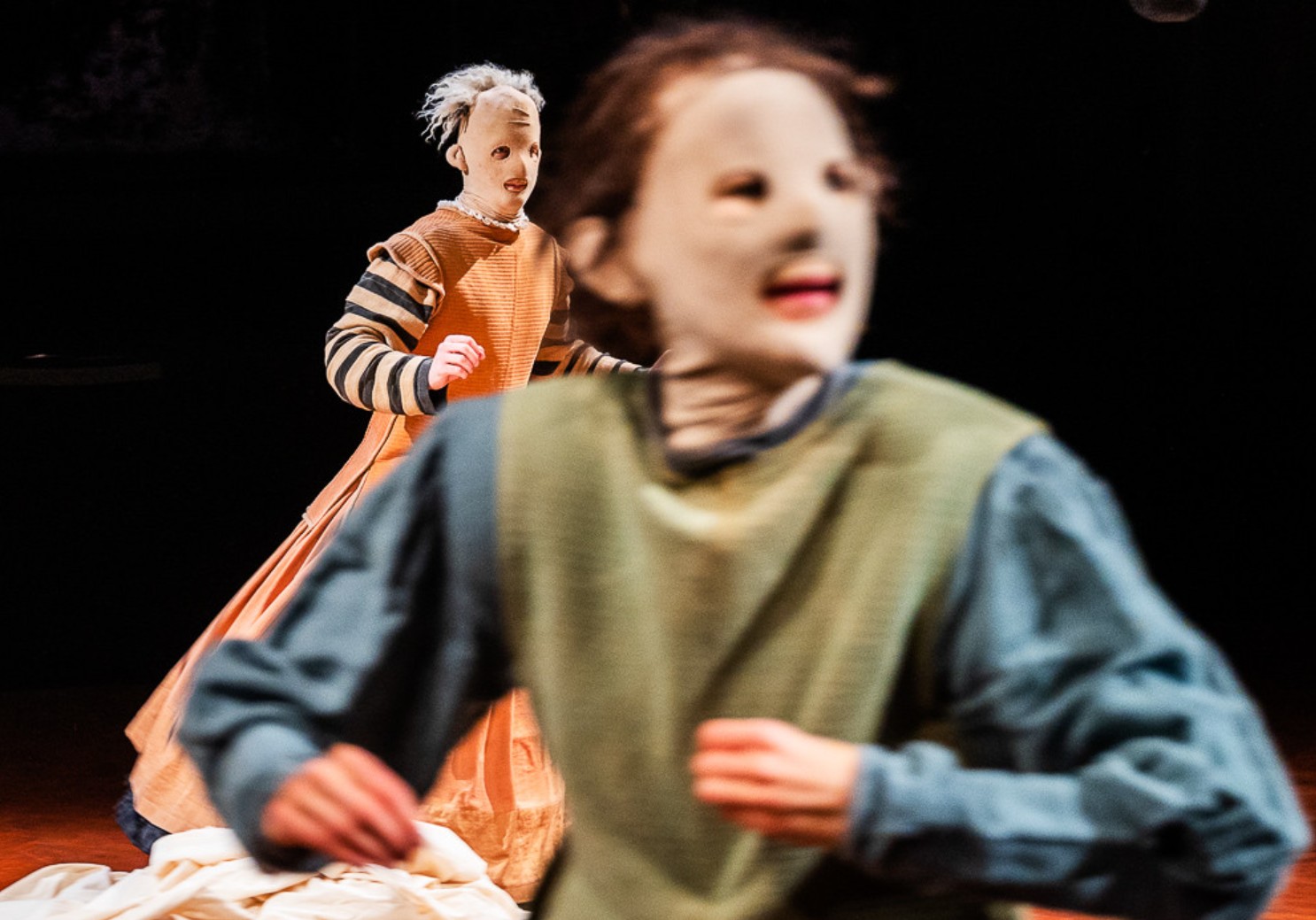 Schauspieler mit Maske im Vordergrund, Marionette mit Maske im Hintergrund
